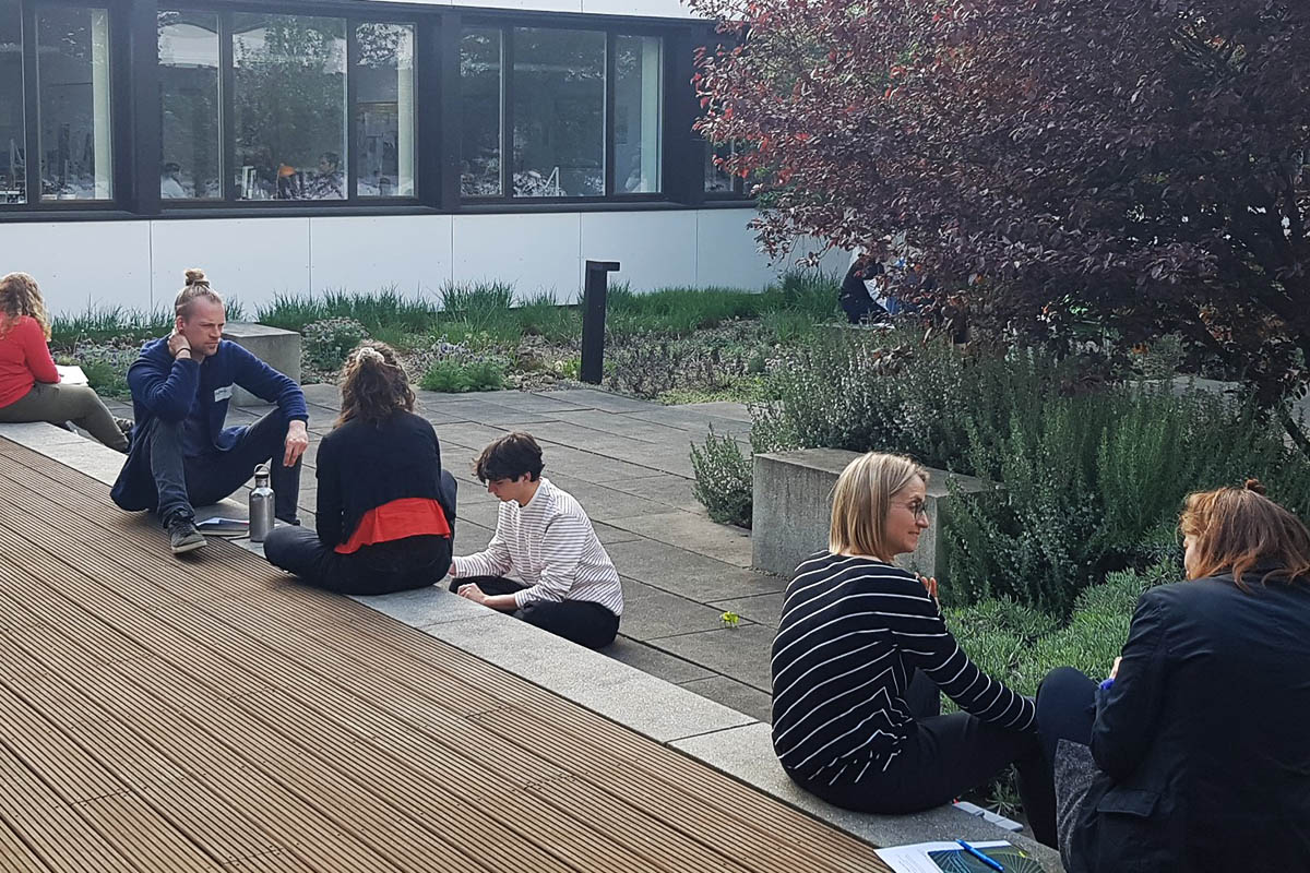 Personen bei der Gruppenarbeit sitzen im Freien. 